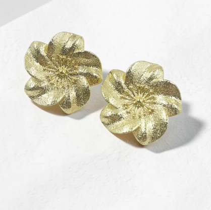 Aretes dorados en forma de flor con acabado texturizado martillado y detalle de polen central en relieve.