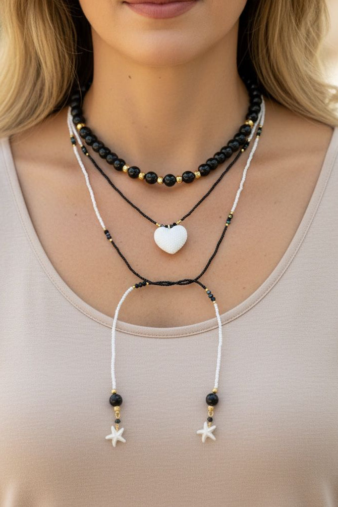 Collar Aurora Corazonada en tonos rojo, blanco y dorado, con diseño de choker y corbatín largo, detalles perlados y dije decorativo en el centro.