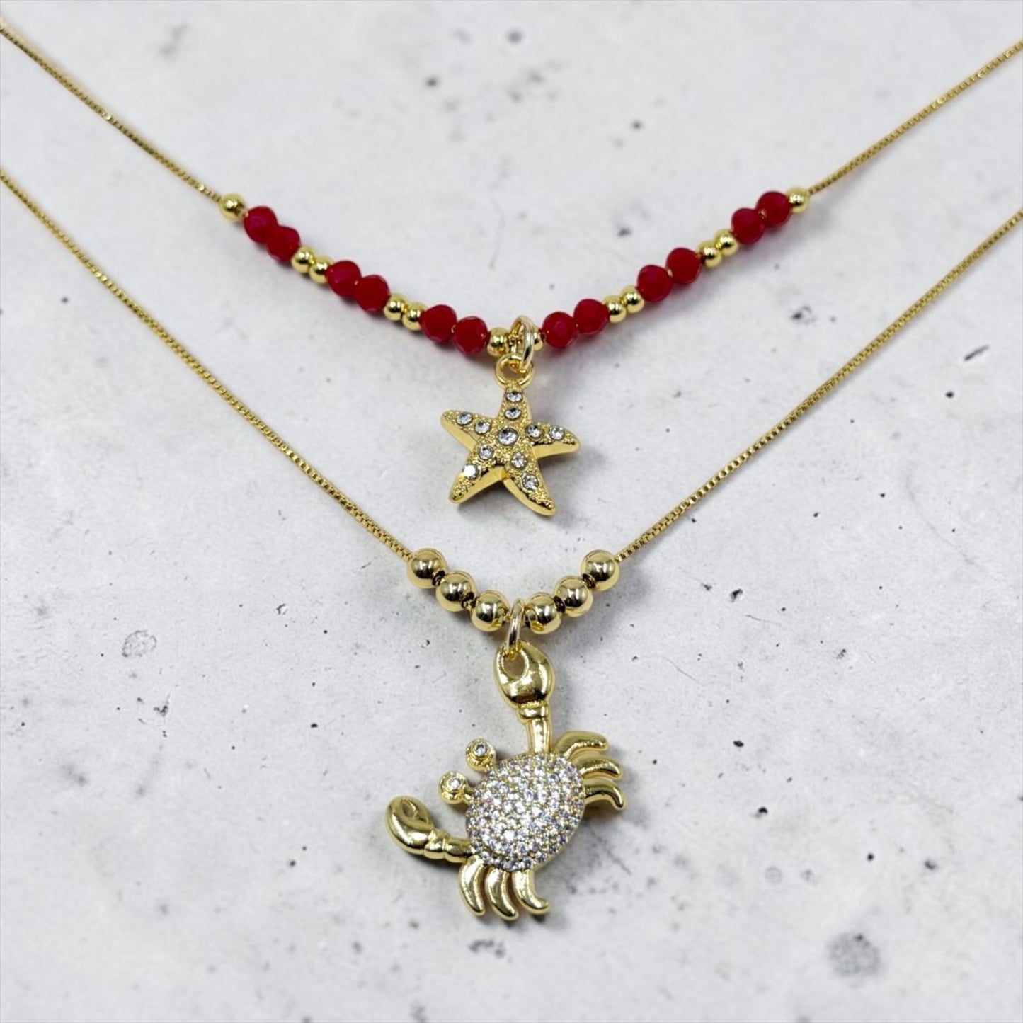 Set de dos collares con detalles decorativos y dijes de estrella y cangrejo.