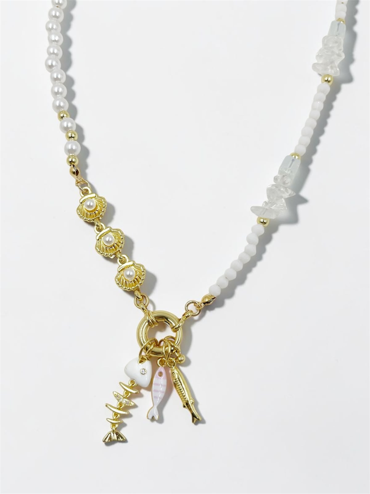 Collar Perlas Frescura del Mar con perlas blancas, detalles decorativos en tonos claros y dorados, y dijes marinos colgantes.