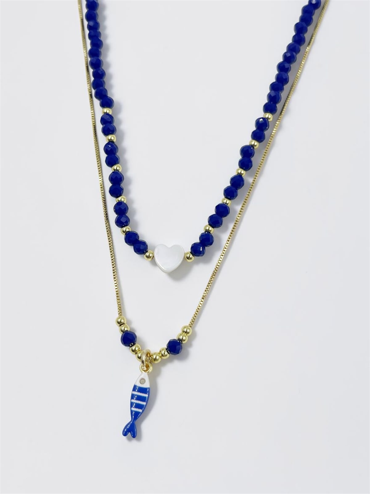 Set de dos collares con choker de cuentas y dije de corazón, acompañado de un collar largo con dije de pez para mujer.