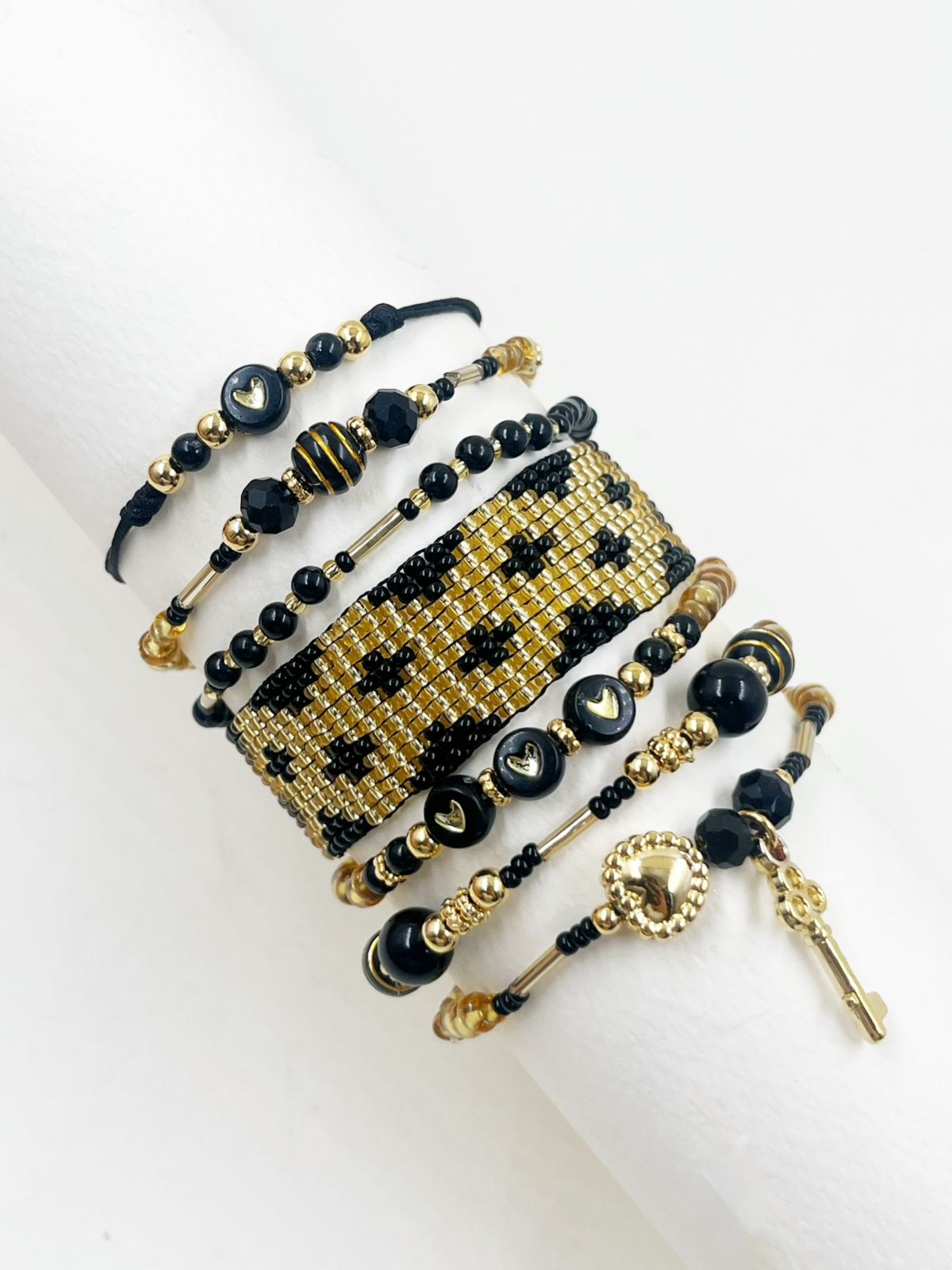 Maxipulsera Night Gold Key con múltiples vueltas, detalles de corazones, llave decorativa y tejido artesanal.