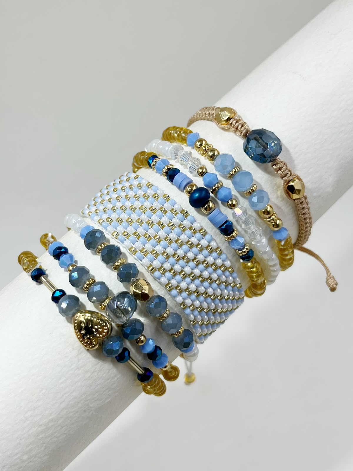 Maxipulsera de 8 vueltas con banda central tejida, cuentas facetadas, esferas de diferentes tamaños, detalles geométricos y dije de corazón.