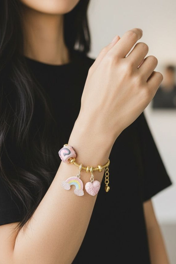 Pulsera de guaya dorada con dijes de resina y detalle de arcoíris que brilla en la oscuridad