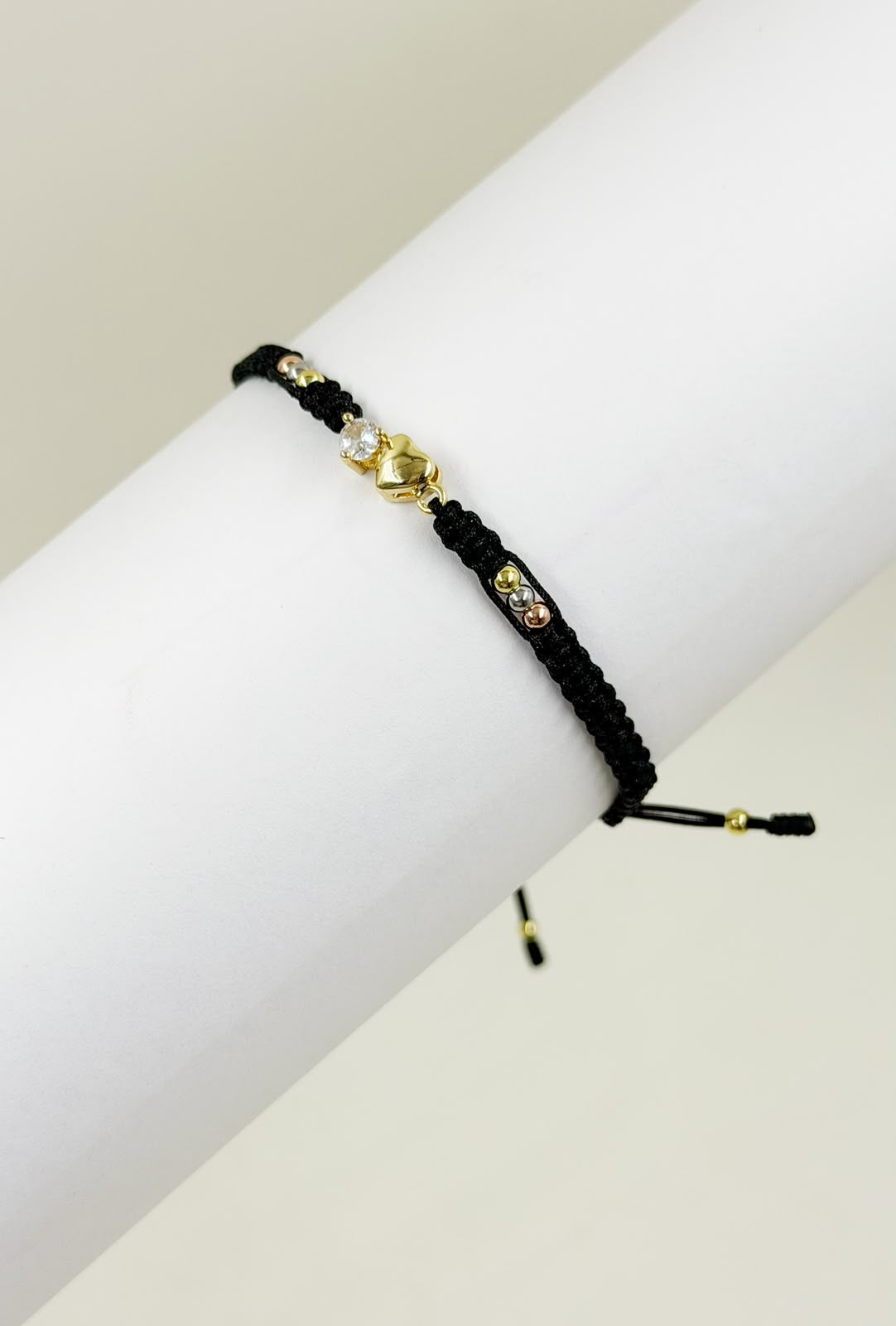 Pulsera artesanal con dije de corazón inflado y detalle central brillante.