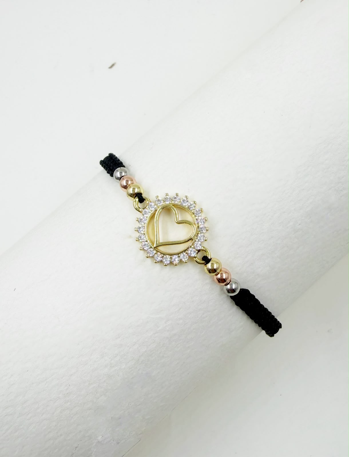 Pulsera artesanal con dije de corazón calado y detalles brillantes, de diseño delicado y romántico.