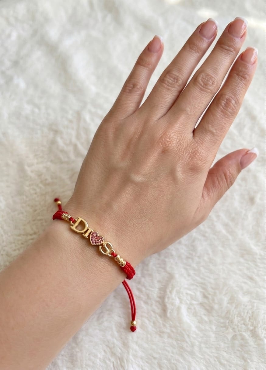 Pulsera artesanal sencilla con dije que lleva la palabra Dios, de diseño delicado y significativo.