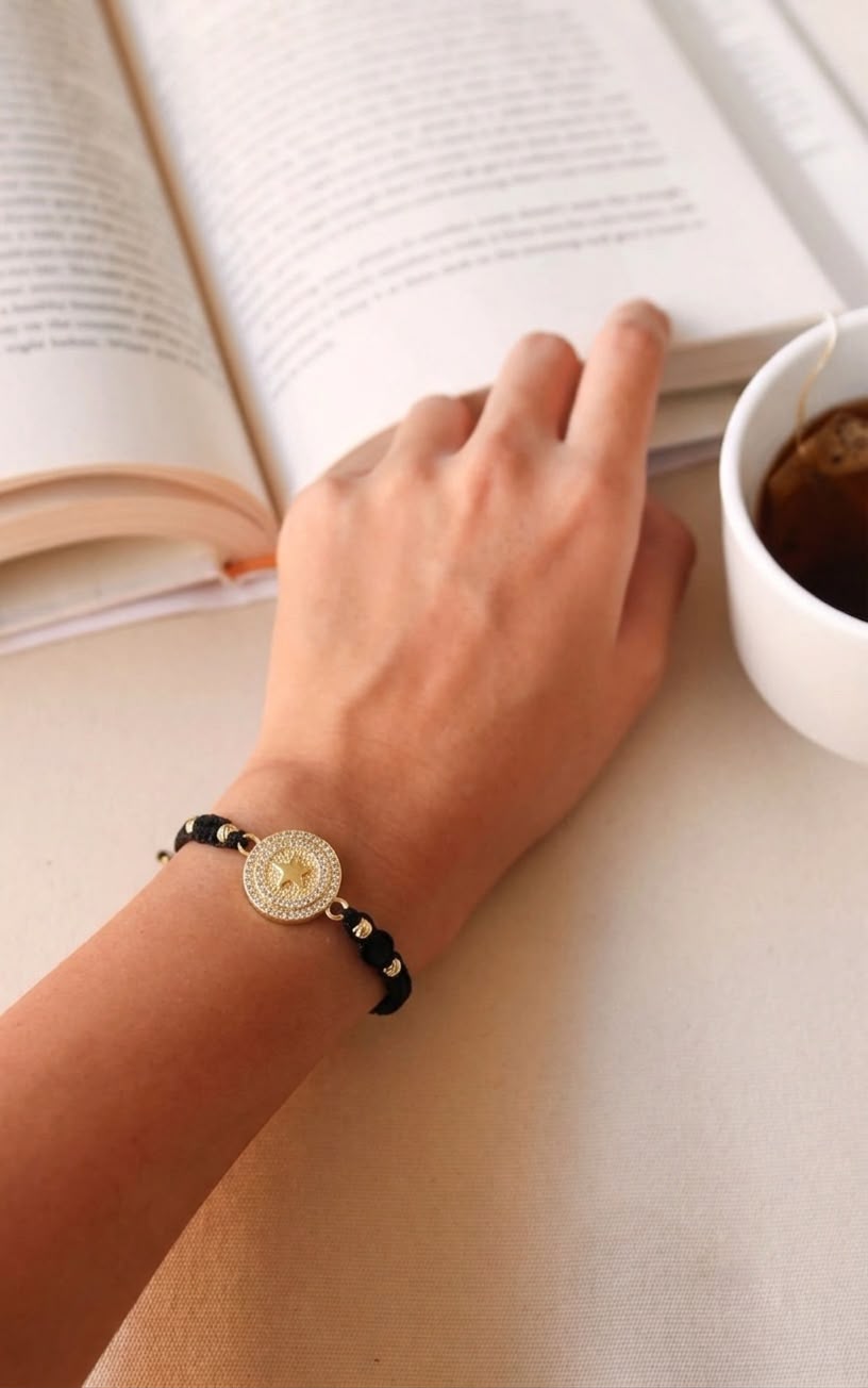 Pulsera artesanal con dije de medalla y estrella grabada, decorada con detalles brillantes.
