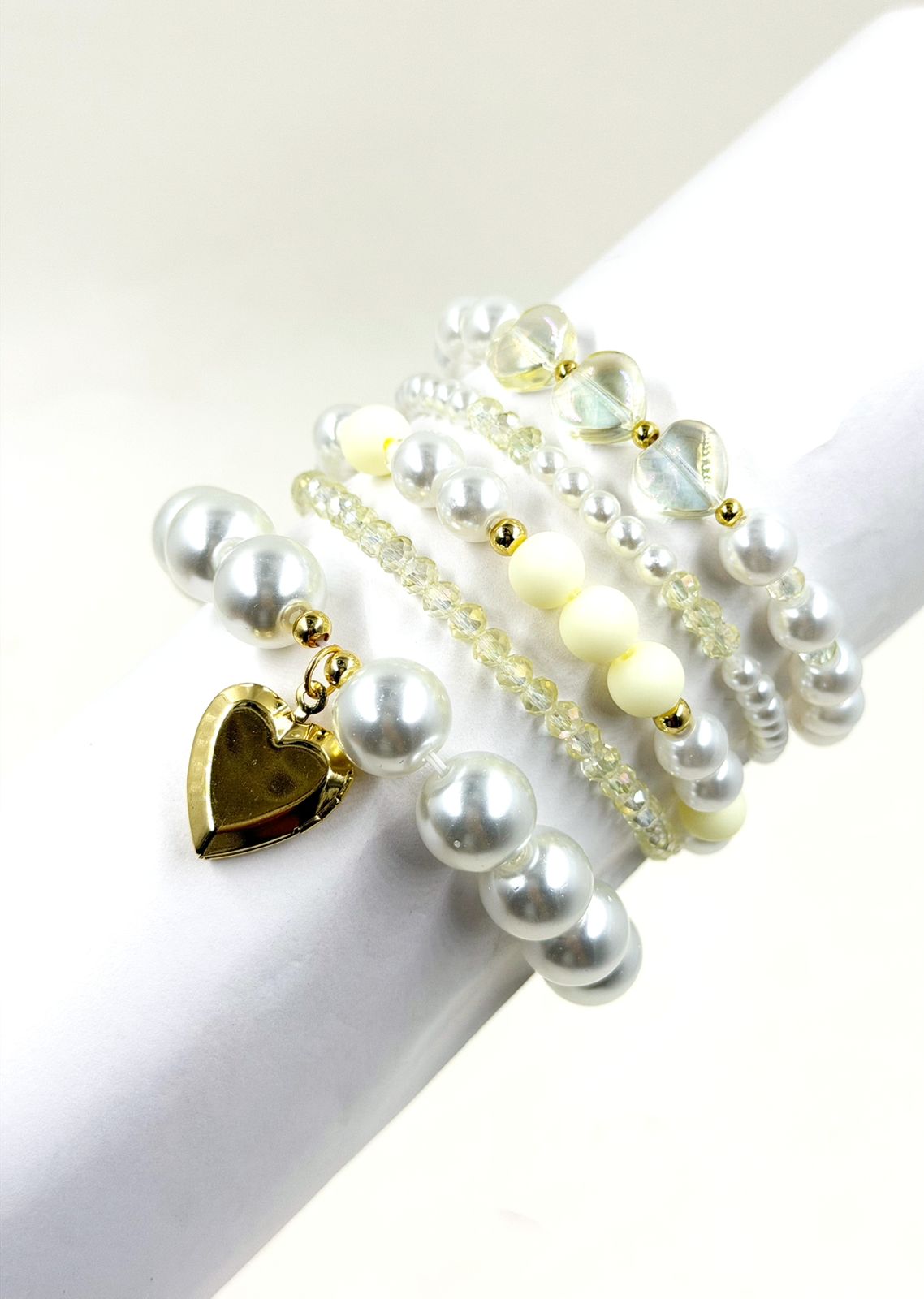 Pulsera femenina con cuentas decorativas de diferentes tamaños y dije de corazón sobre la muñeca.