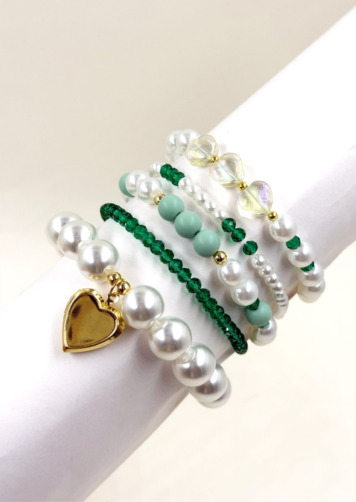 Pulsera femenina con cuentas decorativas de diferentes tamaños y dije de corazón sobre la muñeca.