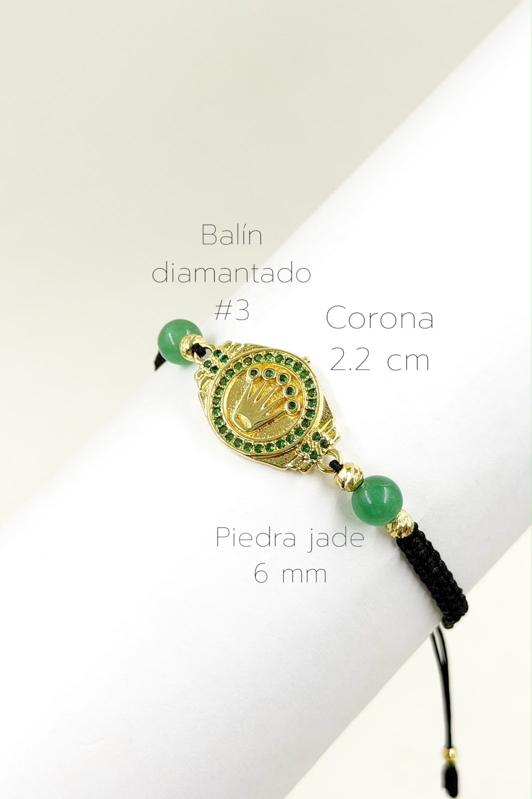 Pulsera artesanal con dije de corona sobre fondo dorado, de diseño delicado y elegante.