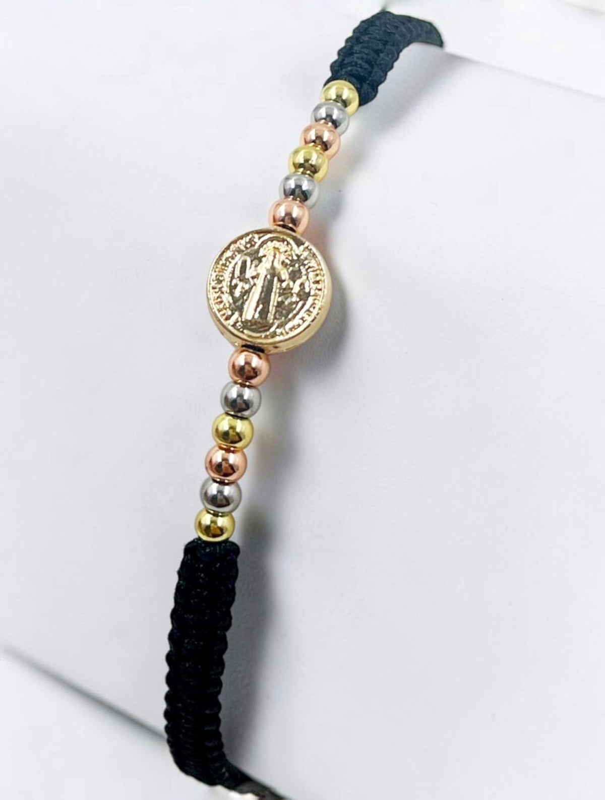 Pulsera artesanal con dije de San Benito, de diseño delicado y elegante.