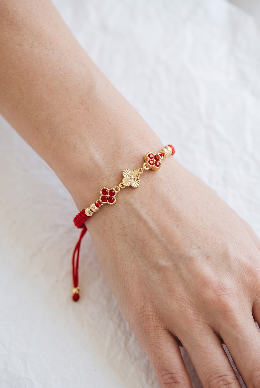 Pulsera artesanal con tres tréboles de cuatro hojas y diseño delicado.