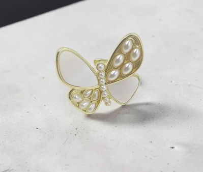 Anillo Mariposa Nácarada Splendor con diseño de mariposa en acabado dorado y detalles de perlas nacaradas sobre fondo neutro.