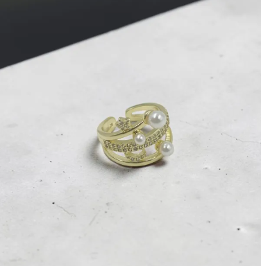Anillo Noche Perlada ajustable en acabado dorado con perlas decorativas y circones brillantes para mujer.
