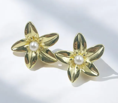 Aretes dorados tipo topo con silueta de flor y una perla central brillante y esférica.