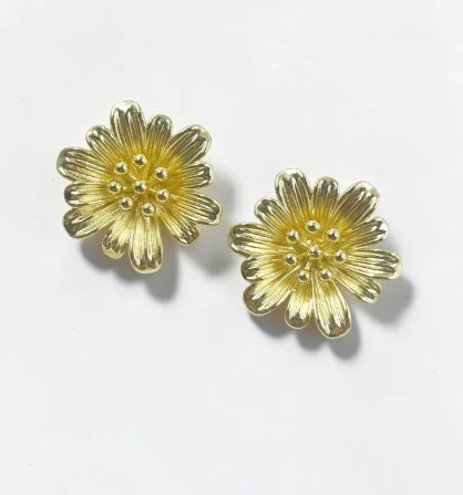 Aretes dorados tipo topo con silueta de flor clásica y un detalle texturizado en el centro.