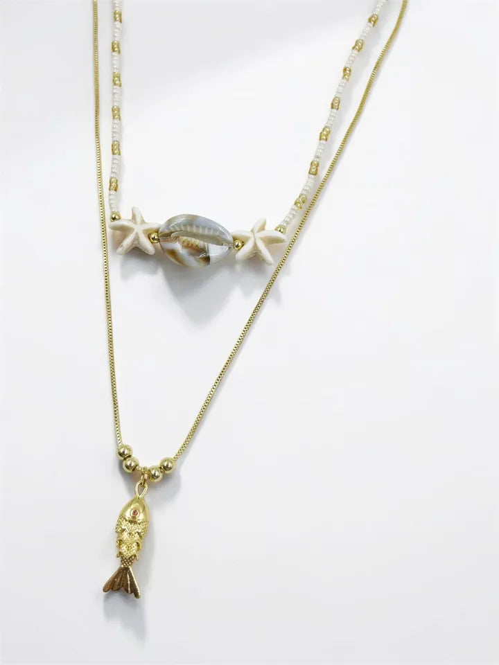 "Collar Modo Playero con choker de mostacilla checa y dije pez dorado articulado"

"Collar artesanal doble pieza con concha nácar y estrellas fósil imitación"