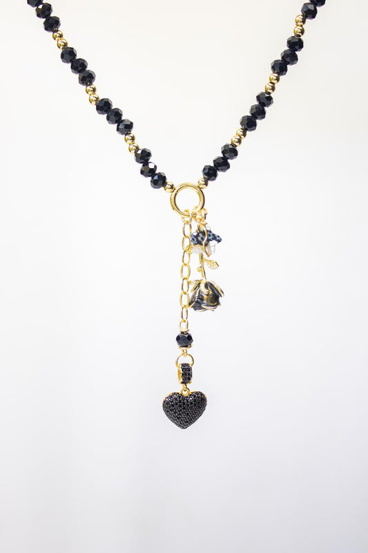 Collar Brillo del Alma elaborado con cristales Murano dorados y dije en forma de corazón con microcircones negros, sobre fondo blanco, diseño artesanal elegante.