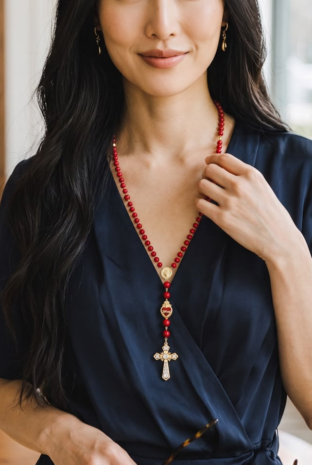 Collar de cuentas con dijes religiosos, corazón y cruz decorativa.