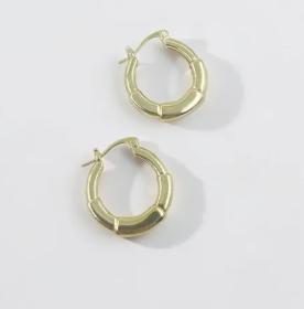 Aretes tipo candonga dorada gruesa con diseño acorazado de relieve geométrico.