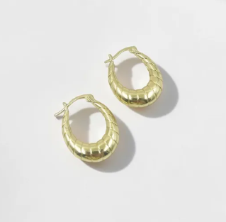 Aretes tipo candonga dorada con silueta ondulada y textura anillada en relieve.