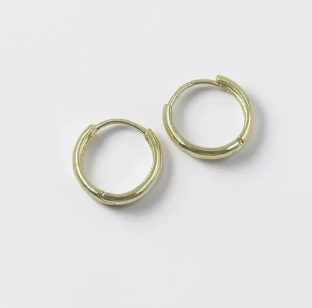 Aretes tipo candonga lisa dorada con un diseño circular clásico y acabado pulido brillante sobre un fondo neutro.