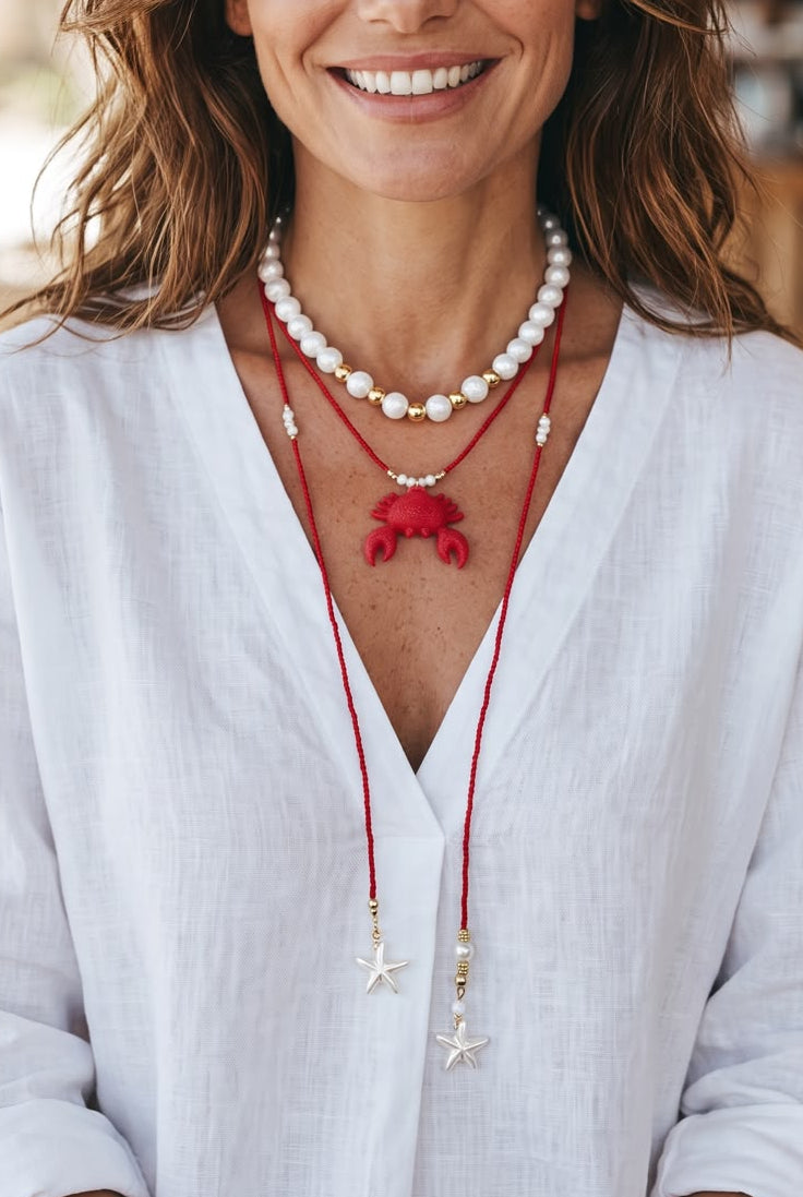 Collar Aurora Marina en tonos rojo, blanco y dorado, con diseño de choker y corbatín largo, detalles perlados y dije decorativo en el centro.