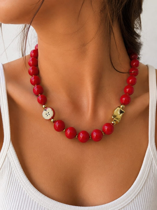 Collar chunky con cuentas de acabado liso, dije de media manzana y detalle decorativo de diseño orgánico.