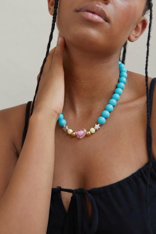 Collar de esferas blancas voluminosas con dije de corazón morado y detalles de estrellas