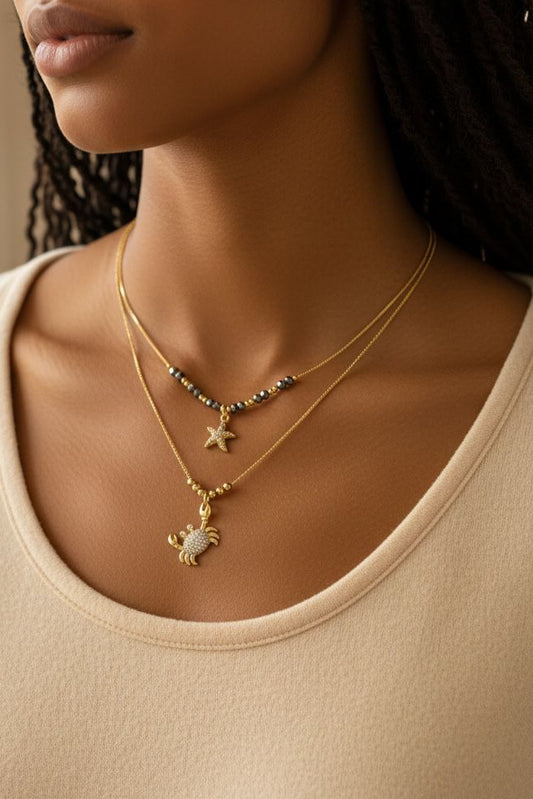Set de dos collares con detalles decorativos y dijes de estrella y cangrejo.