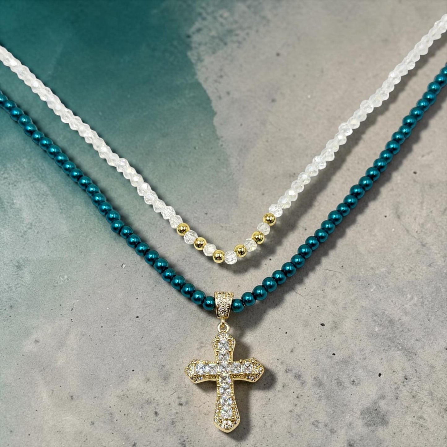 Set de dos collares con cuentas, cristales, detalles dorados y dije de cruz.
