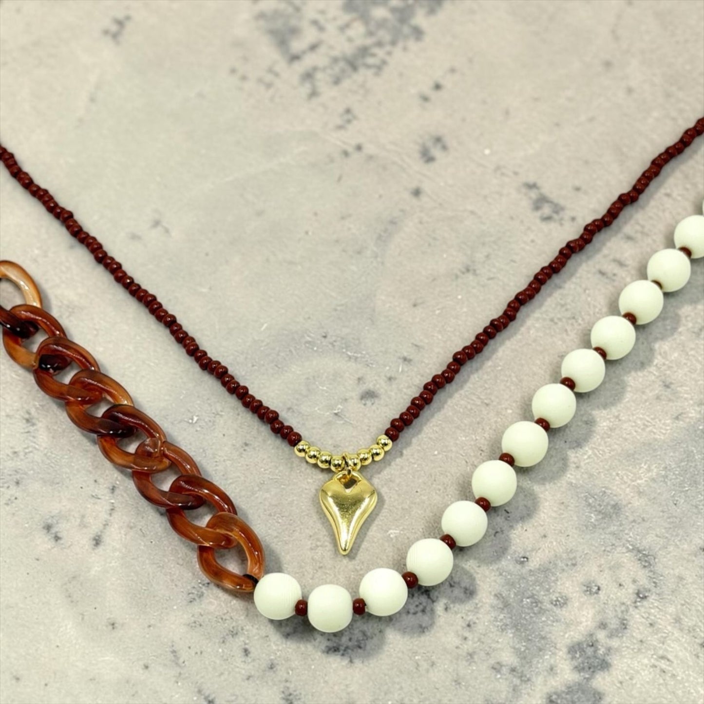 Collar de diseño dinámico con cuentas, eslabones y dije decorativo.