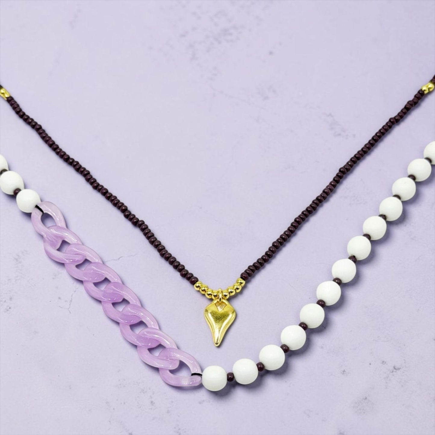 Collar de diseño dinámico con cuentas, eslabones y dije decorativo.