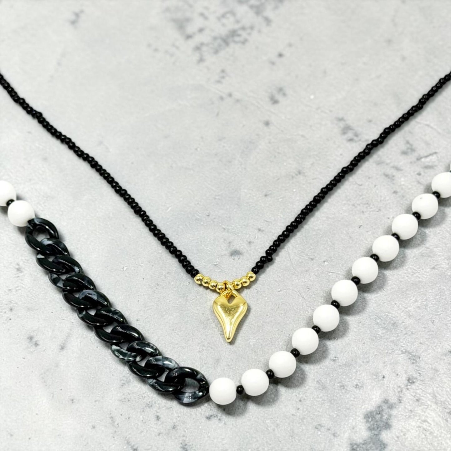 Collar de diseño dinámico con cuentas, eslabones y dije decorativo.