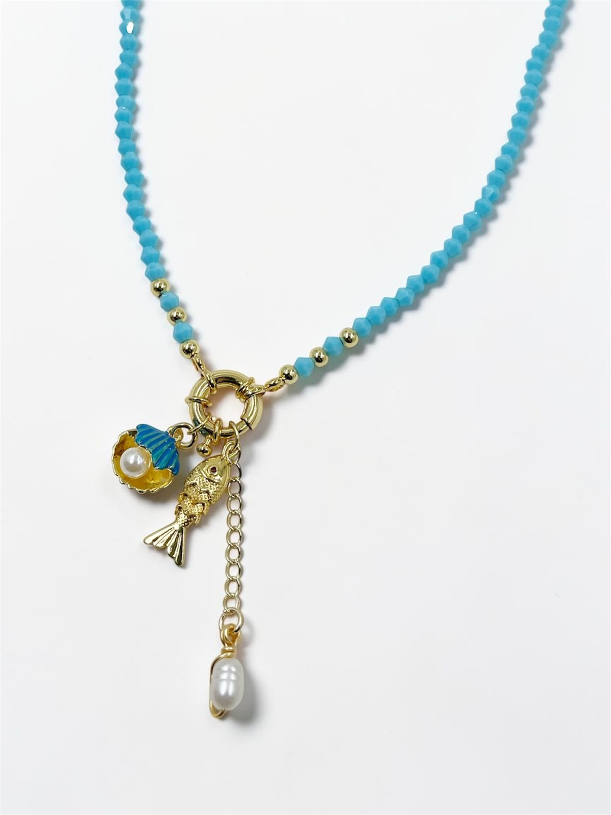 Collar Marea Costera con dije de concha, pez articulado y detalles perlados inspirados en el océano.