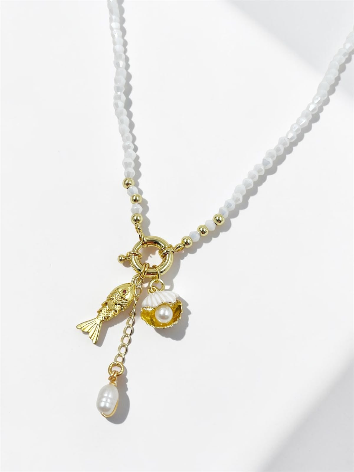 Collar Marea Costera con dije de concha, pez articulado y detalles perlados inspirados en el océano.