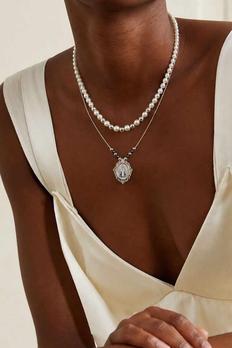 Collar de dos piezas con diseño en capas, medalla de la Virgen con detalles azules y gargantilla de estilo elegante.