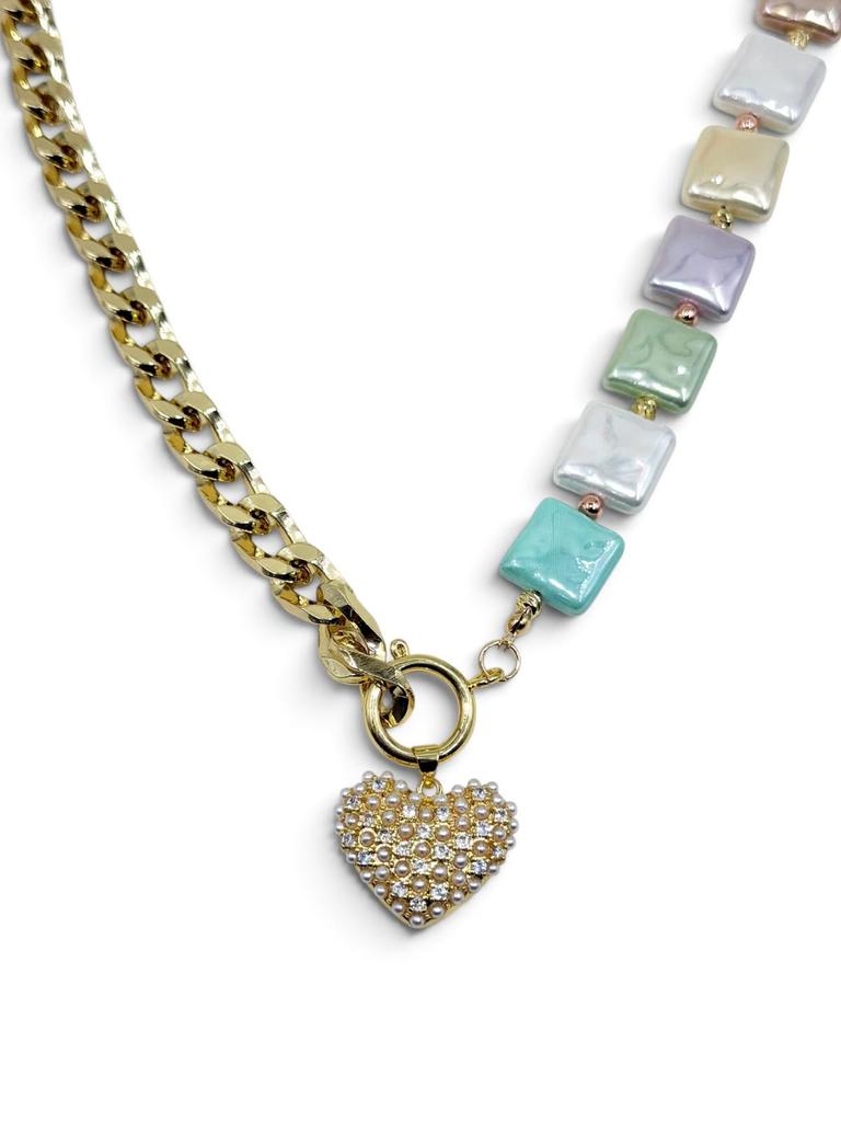 Collar asimétrico con cadena dorada, piezas en tonos pastel y corazón central recamado de pequeños destellos.