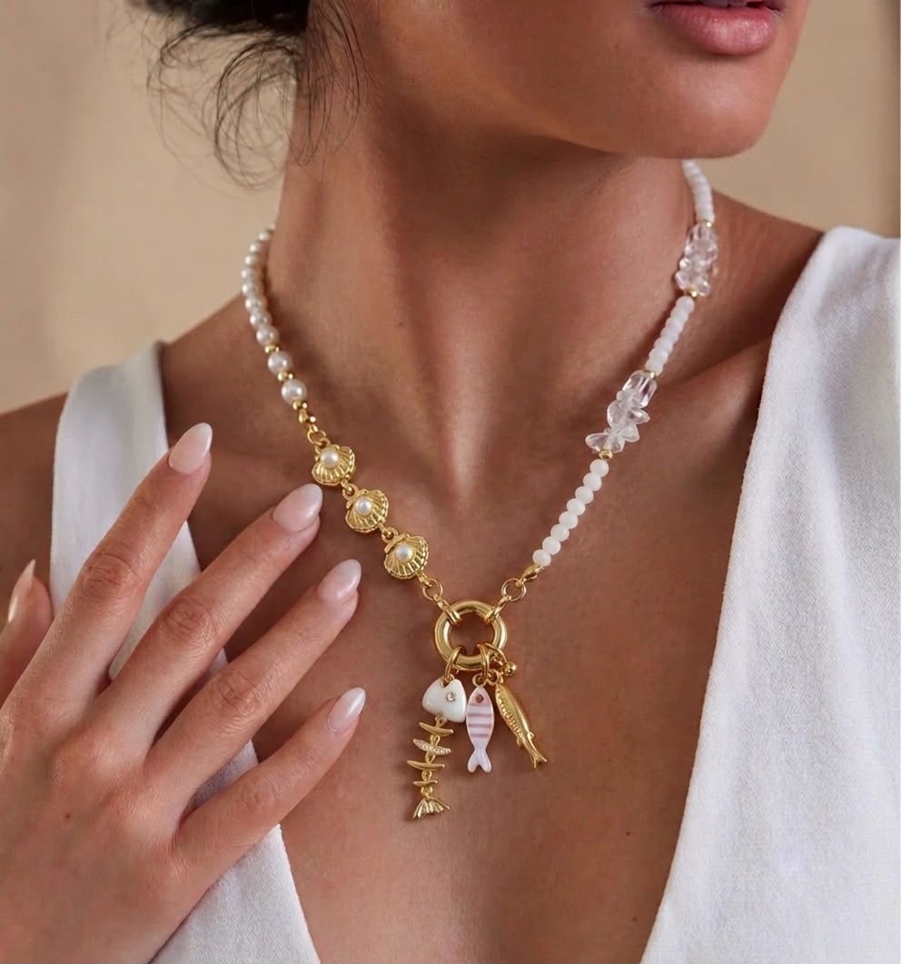 Collar Perlas Frescura del Mar con perlas blancas, detalles decorativos en tonos claros y dorados, y dijes marinos colgantes.