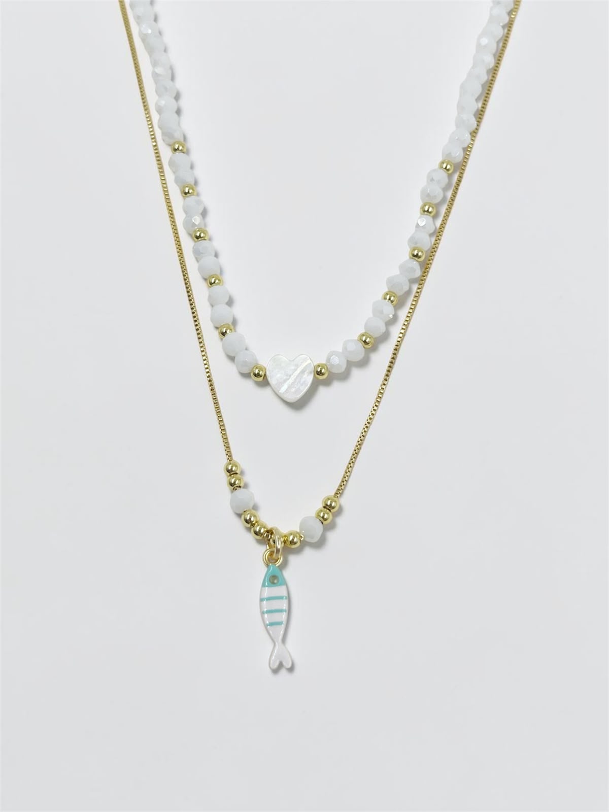 Set de dos collares con choker de cuentas y dije de corazón, acompañado de un collar largo con dije de pez para mujer.