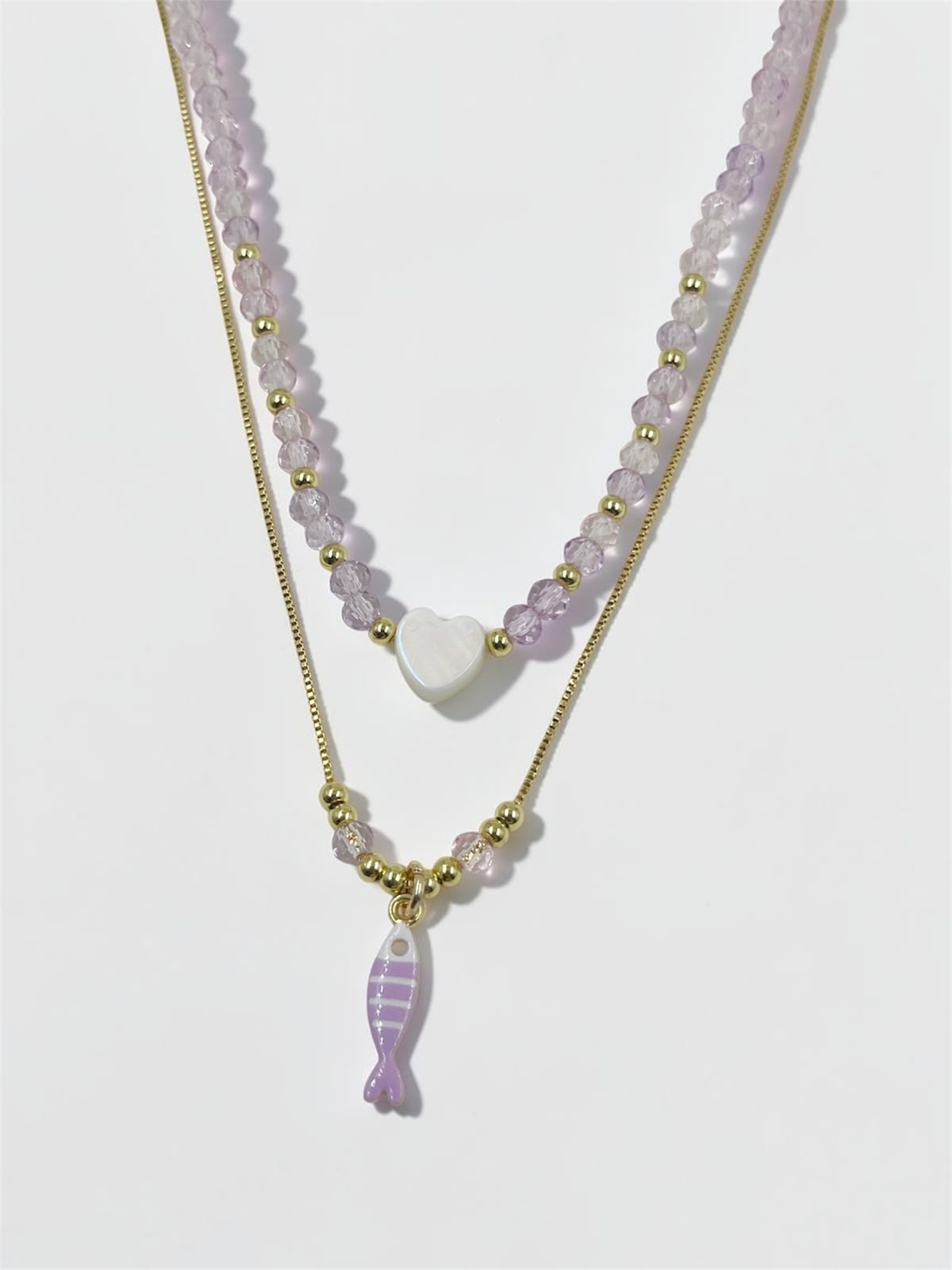 Set de dos collares con choker de cuentas y dije de corazón, acompañado de un collar largo con dije de pez para mujer.
