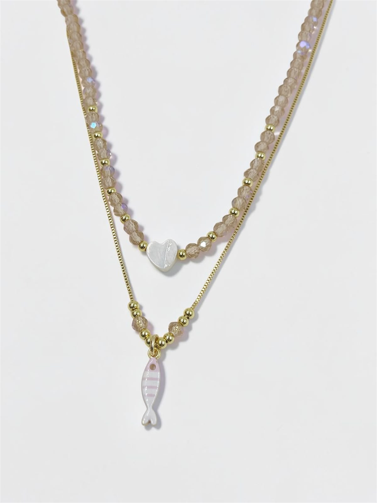 Set de dos collares con choker de cuentas y dije de corazón, acompañado de un collar largo con dije de pez para mujer.