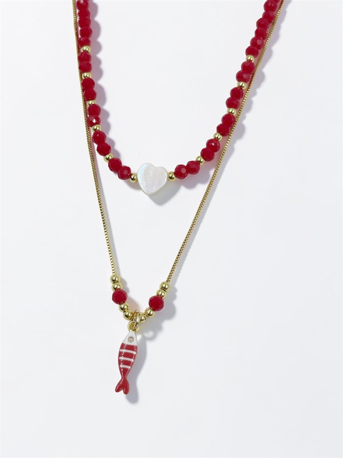 Set de dos collares con choker de cuentas y dije de corazón, acompañado de un collar largo con dije de pez para mujer.