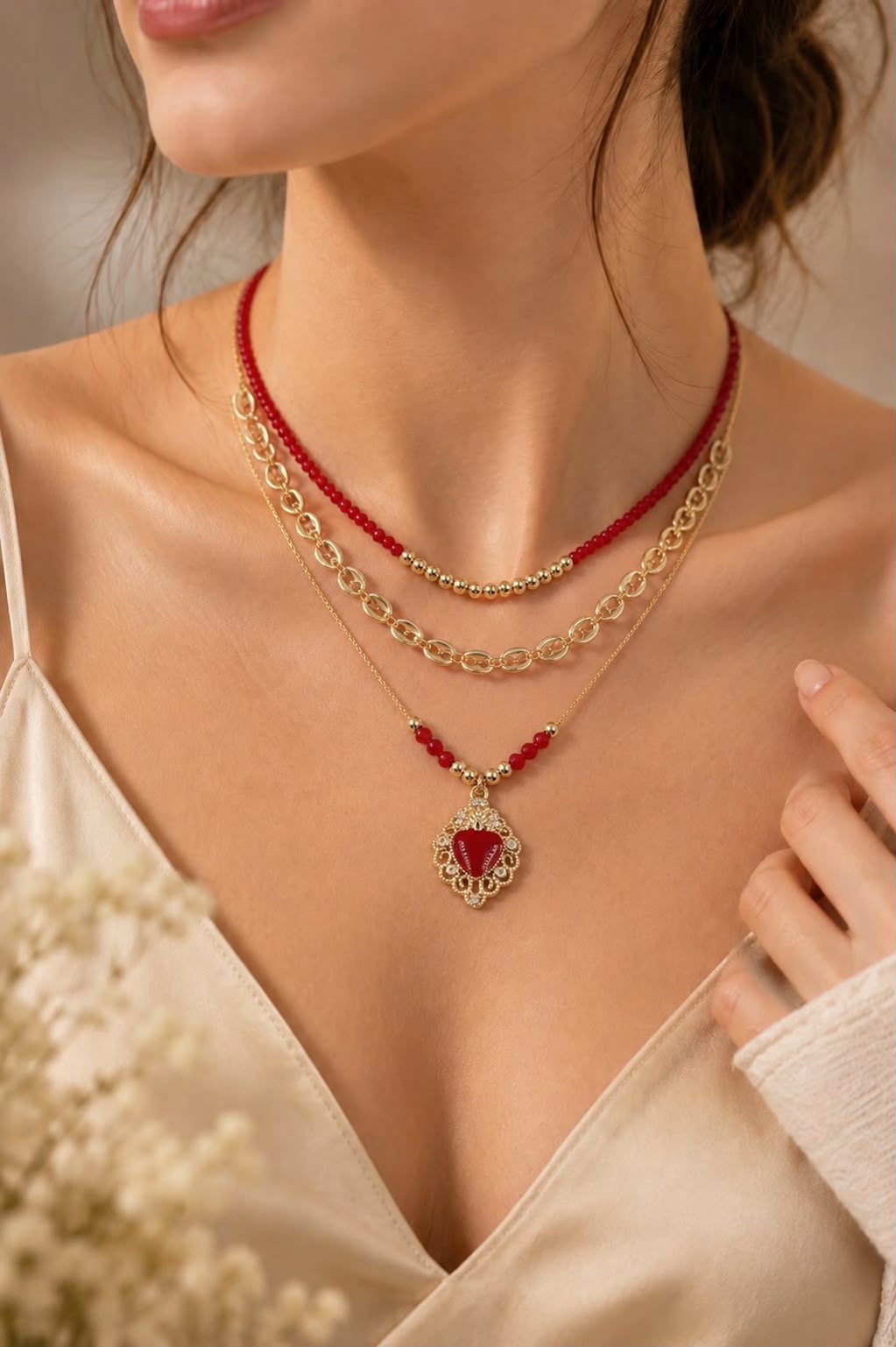 Set de tres collares en capas con detalles rojos y dije del Sagrado Corazón en tono dorado.
