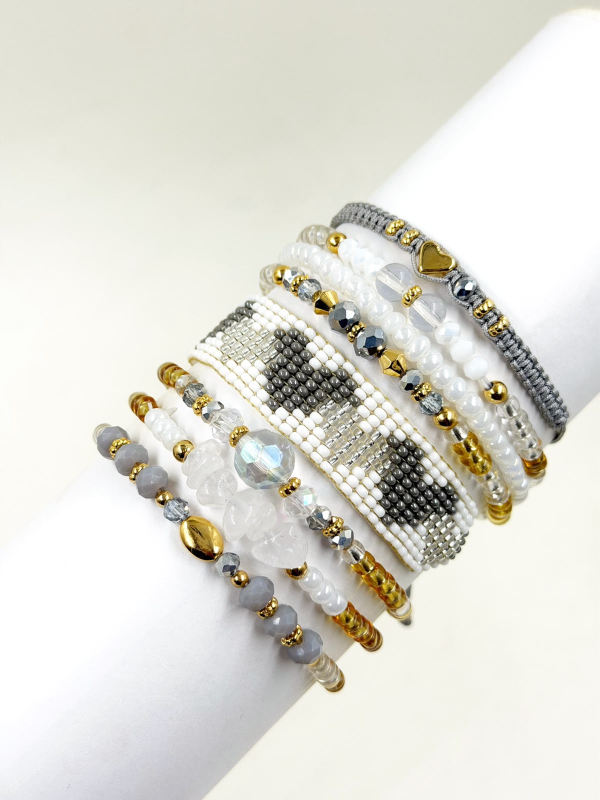 Maxipulsera de 8 vueltas con banda central tejida con patrón de corazones, cuentas facetadas, esferas y detalles decorativos.
