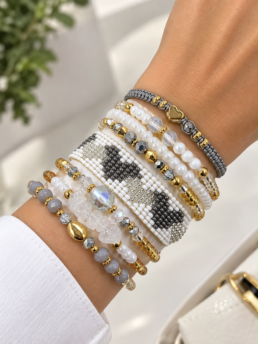 Maxipulsera de 8 vueltas con banda central tejida con patrón de corazones, cuentas facetadas, esferas y detalles decorativos.