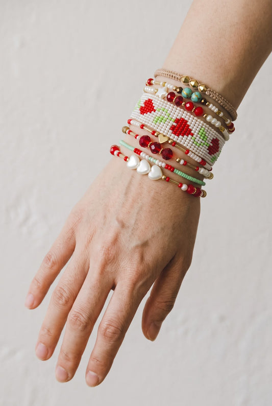 Maxipulsera de 8 vueltas con tejido central de cerezas en forma de corazón, cuentas facetadas, esferas y detalles decorativos.