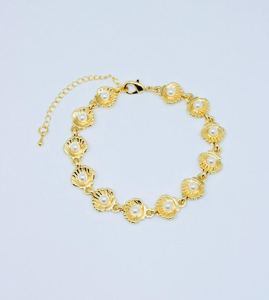 Pulsera Concha Perlada de 17 cm con dijes de conchas doradas y perlas, broche pico de loro y extensión ajustable.