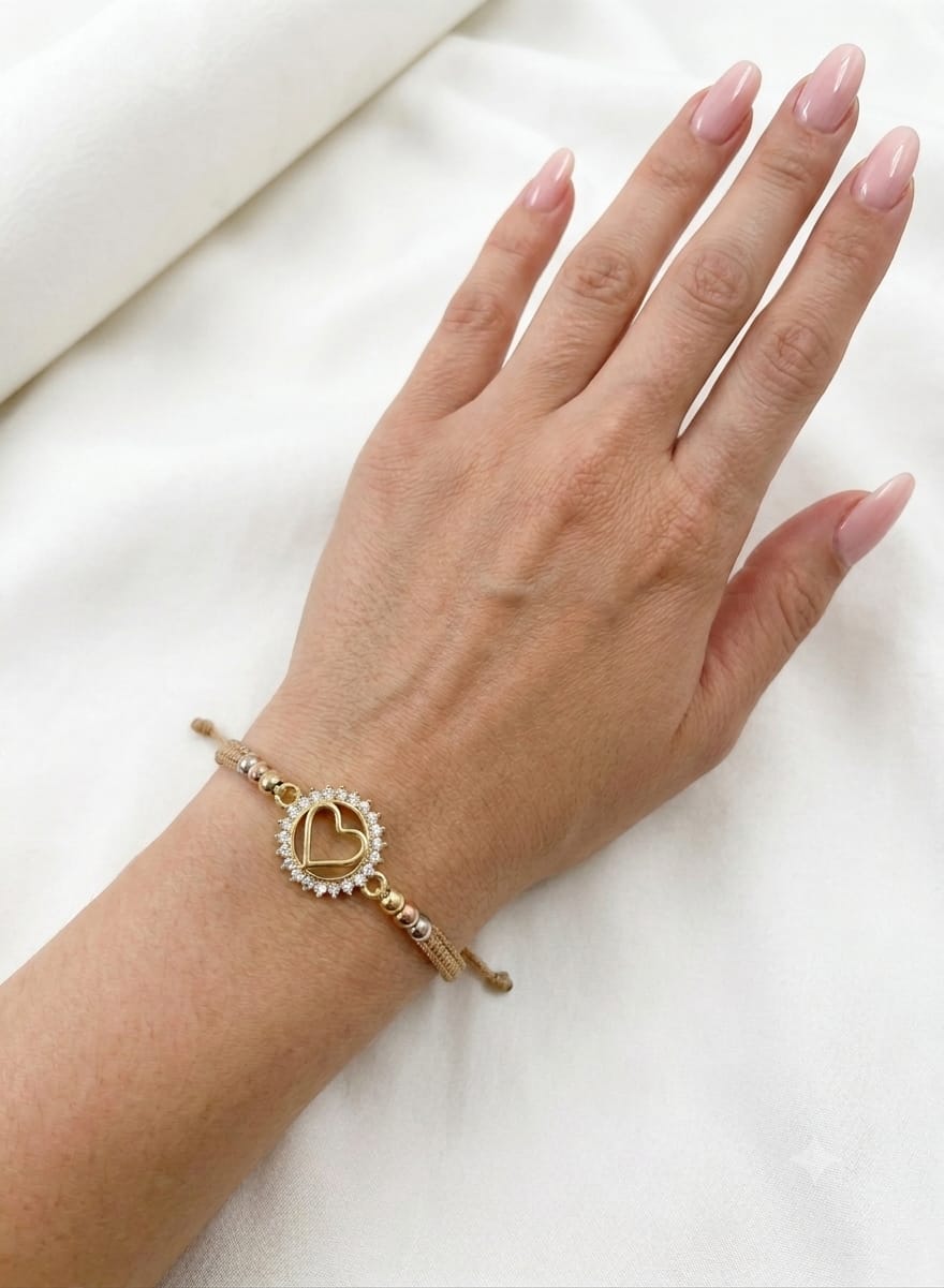 Pulsera artesanal con dije de corazón calado y detalles brillantes, de diseño delicado y romántico.